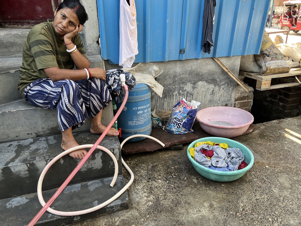 A woman waits for water so she can finish washing her clothes. Savda, Summer 2026. A woman waits for water so she can finish washing her clothes. Savda, Summer 2026.