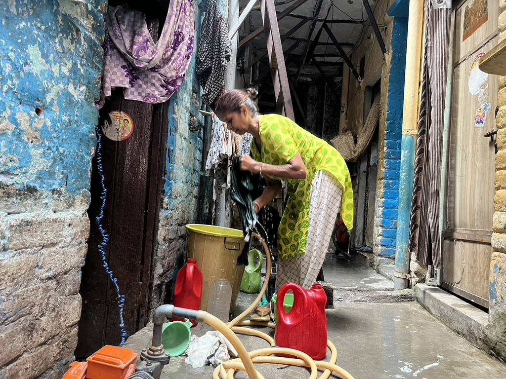 A woman washes clothes at her home in Subhash Camp, Dakshinpuri. Summer 2026. A woman washes clothes at her home in Subhash Camp, Dakshinpuri. Summer 2026.